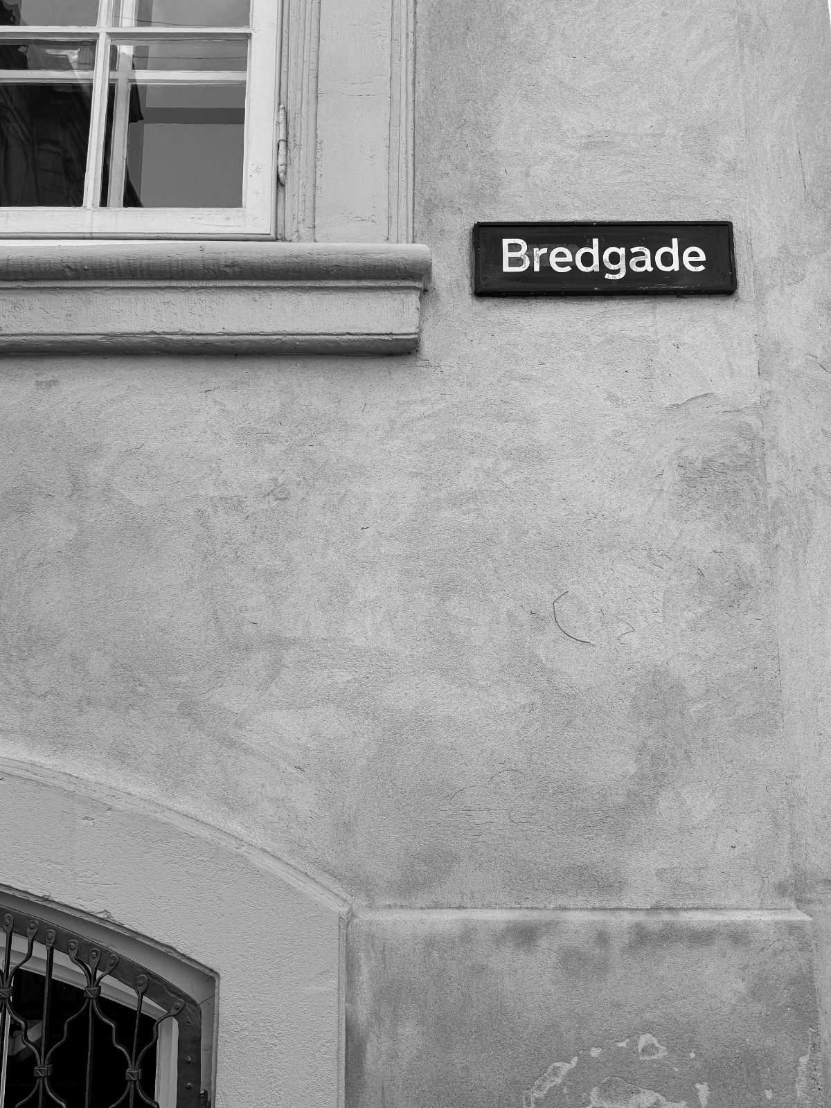 Bredgade-skilt på pudset facade — sort/hvid